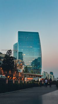 Modern skyscraper in Baku, Azerbaijan, reflecting cityscape at twilight.