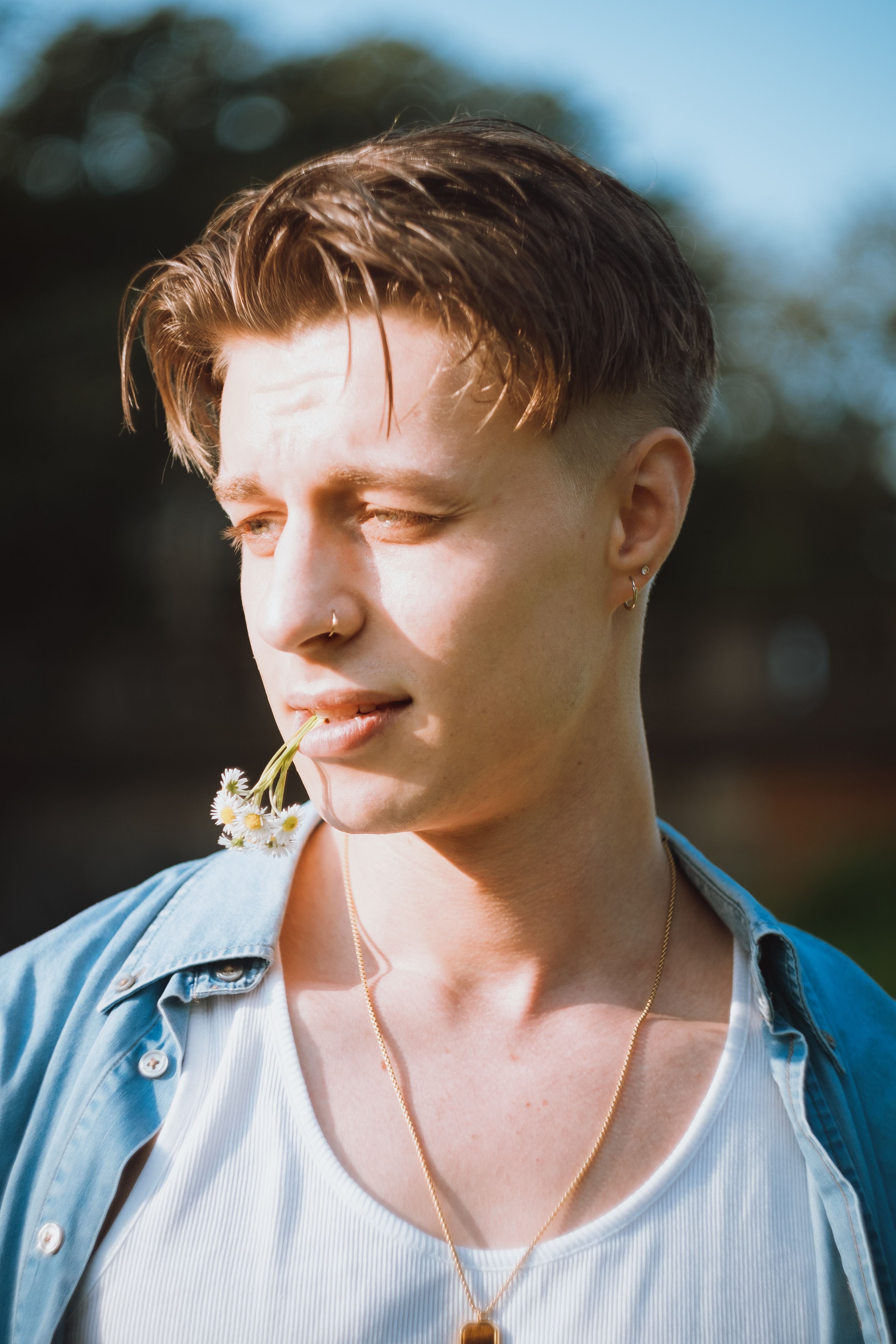 Portrait of a young man with a flower in mouth, exuding a casual style.