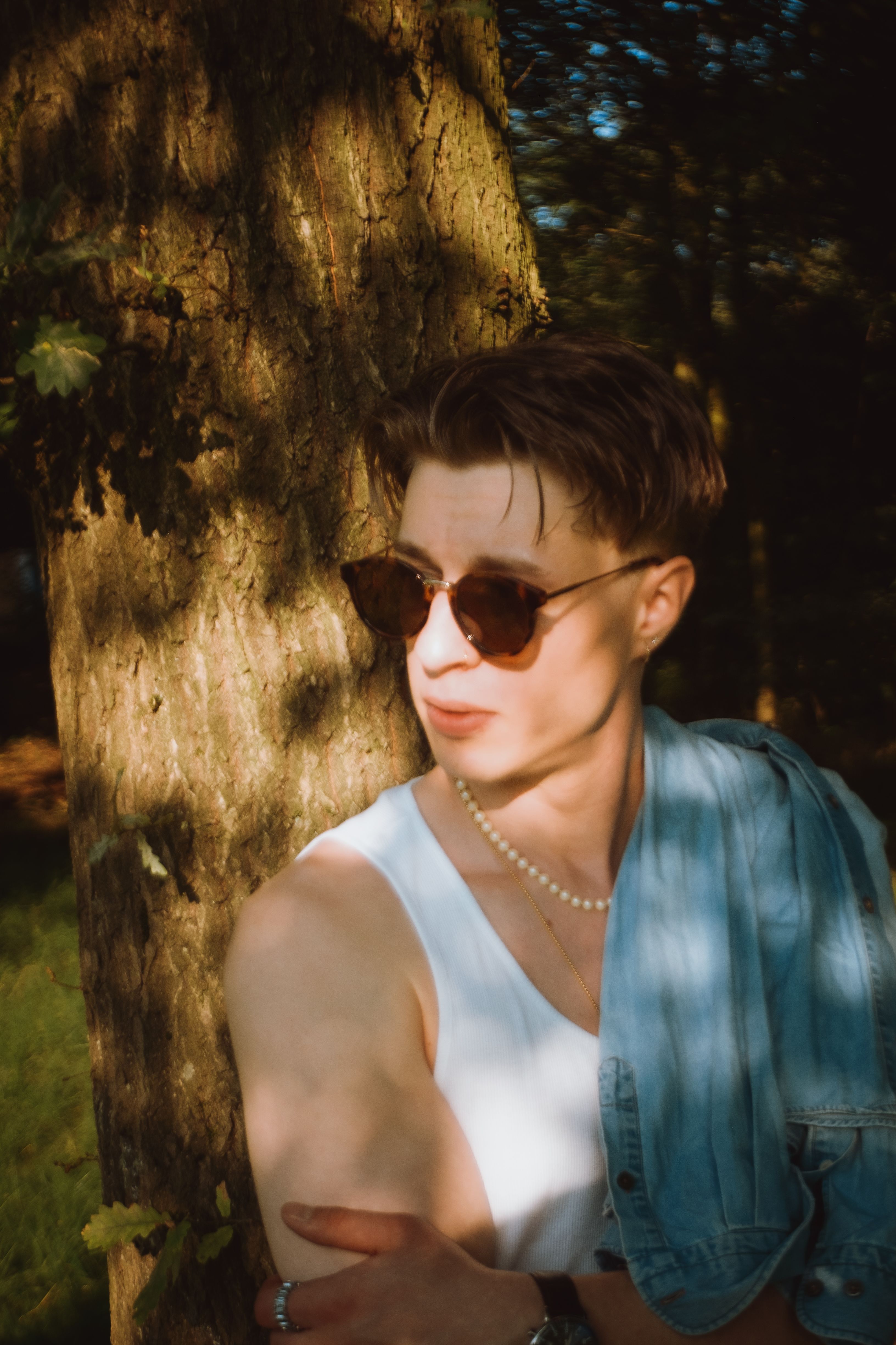 Young Man in Sunglasses Leaning Against a Tree · Free Stock Photo