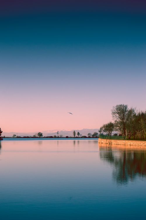 Free Tranquil scene of a serene sunset over a calm lake with clear reflections and a peaceful horizon. Stock Photo