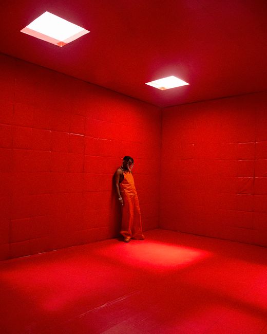 A man standing in an intensely red room with overhead lights in Lagos.