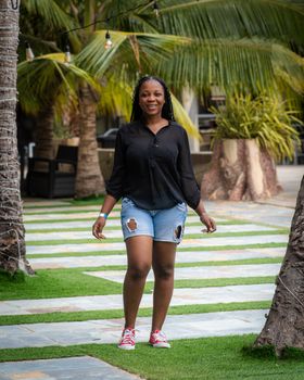 A young woman enjoys a walk in a tropical garden, showing summer fashion.