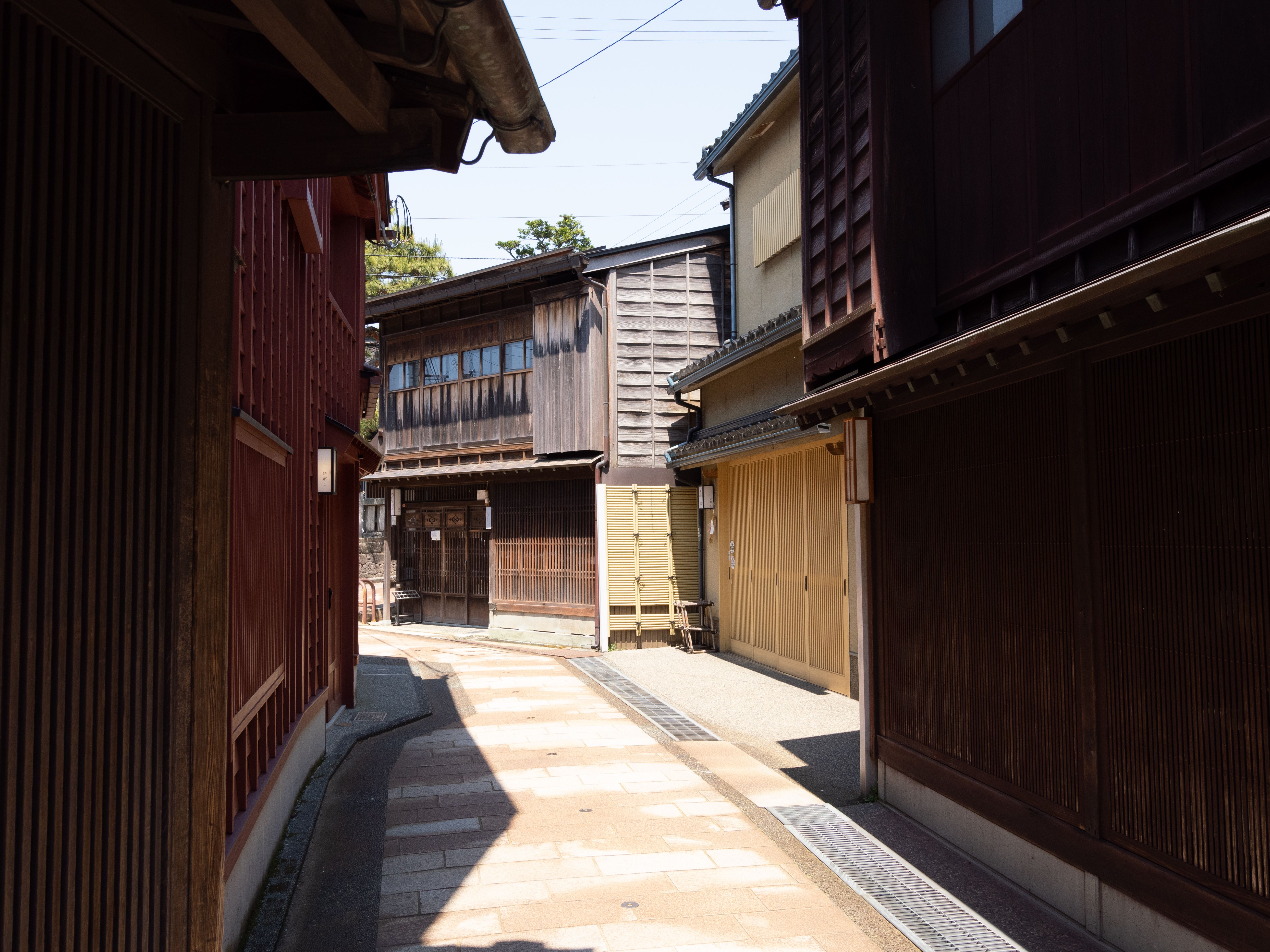 A serene, sunlit alleyway in Kanazawa's historic Higashi Chaya District, Japan.