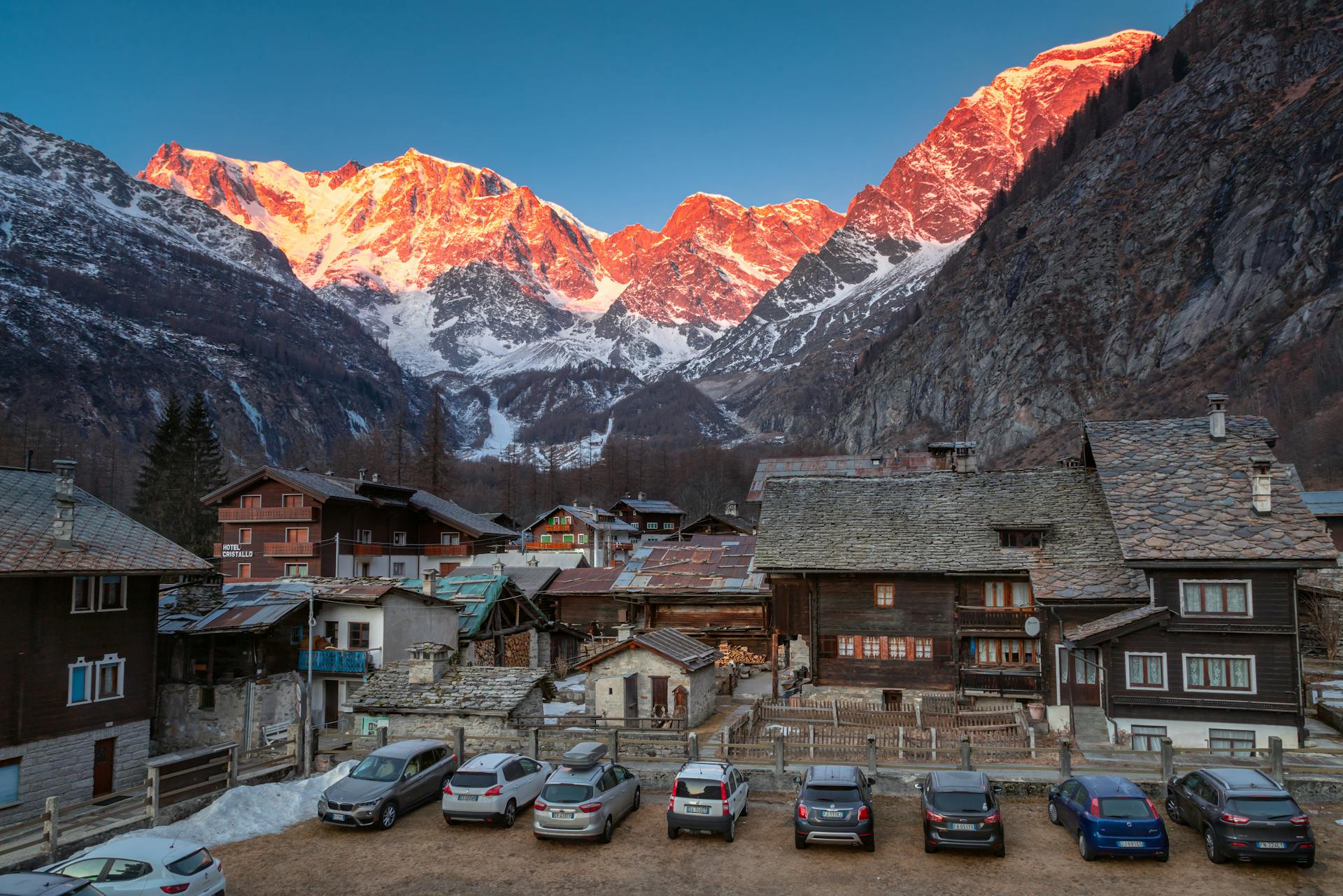 Charming Swiss village nestled in the Alps at sunrise, showcasing traditional wooden chalets and snow-capped peaks.