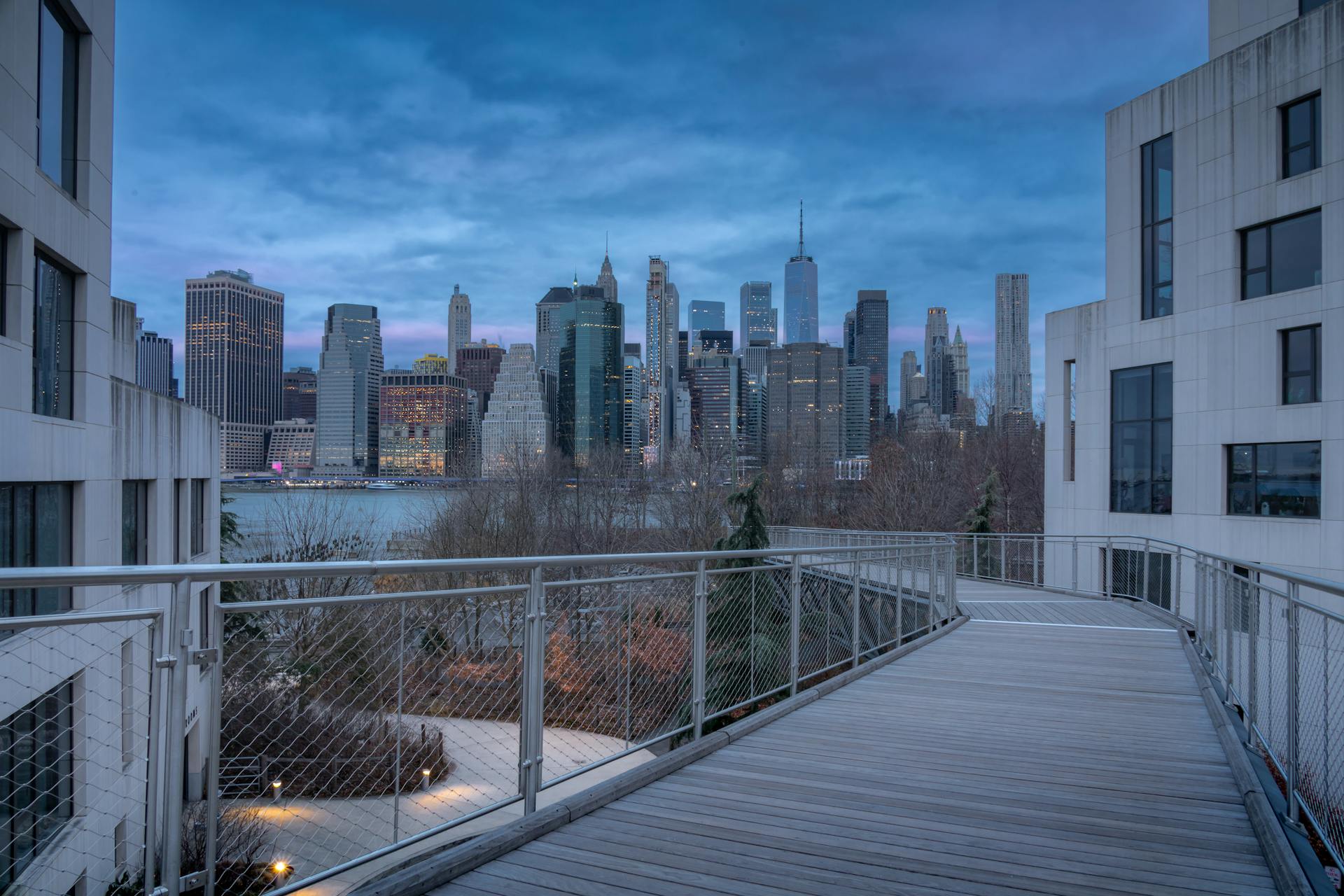 Capture of the iconic Manhattan skyline seen from a bridge at dusk.