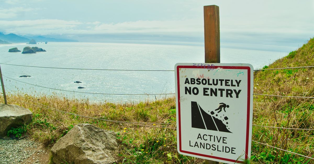 Scenic view of Cannon Beach, Oregon with an active landslide warning sign by the sea.
