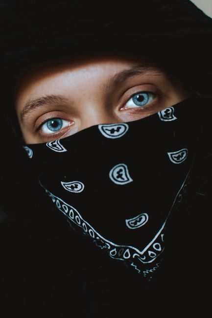 Close-up portrait featuring captivating blue eyes partially covered by a patterned bandana.