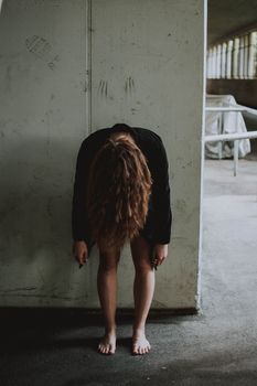 一位年轻女子在室内身体前倾地摆着姿势，营造出一种喜怒无常的艺术氛围