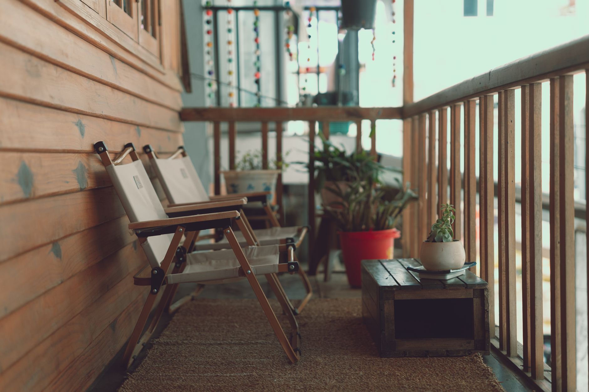 A charming balcony in Dalat, Vietnam featuring wooden chairs and lush plants, offering a relaxing retreat.