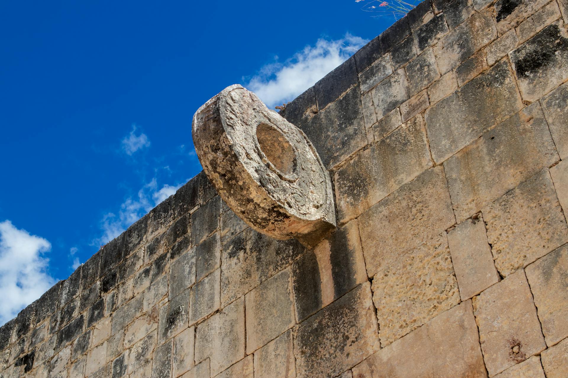 Historic stone ring from Mayan ballcourt at Chichen Itza against a blue sky, showcasing cultural heritage.