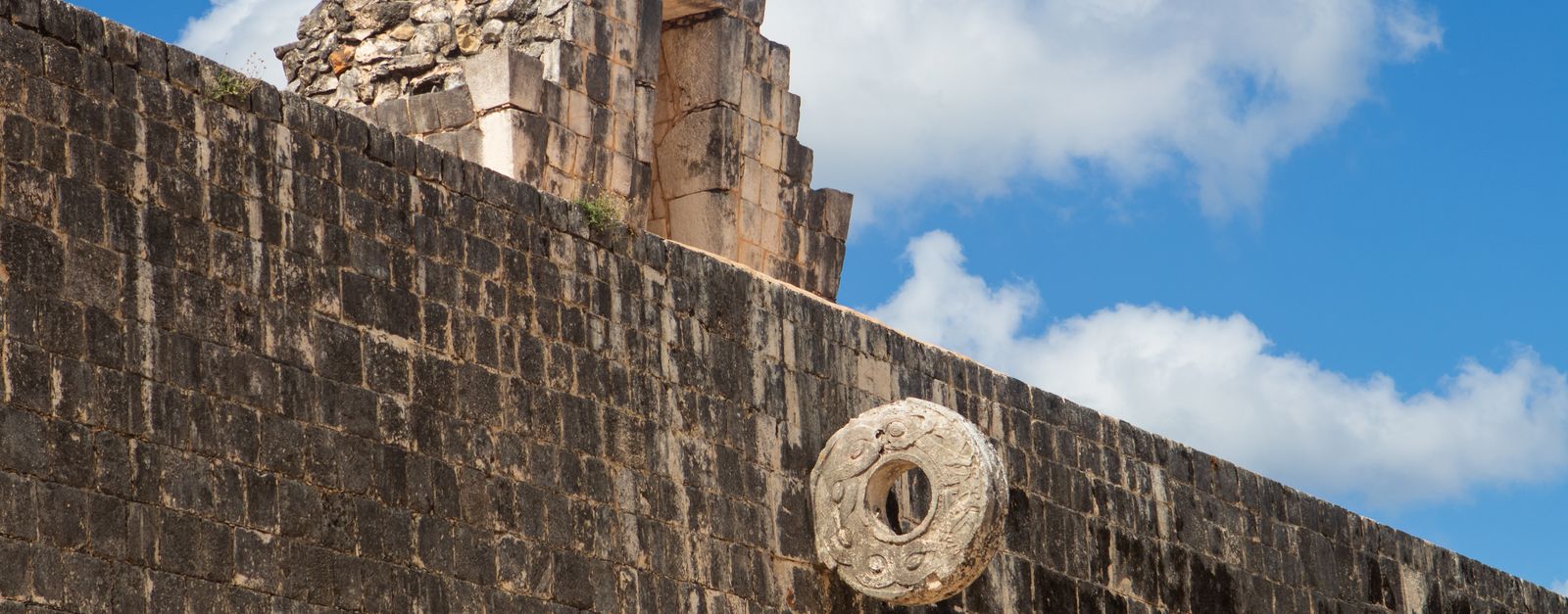 Explore the ancient Mayan ballcourt at Chichen Itza under a vibrant blue sky.
