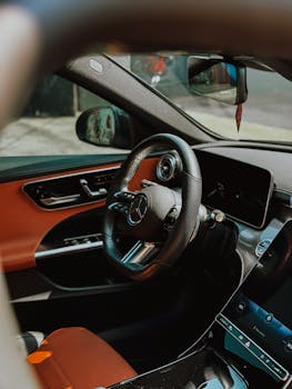 Close-up of a luxury car interior focusing on the steering wheel and dashboard.