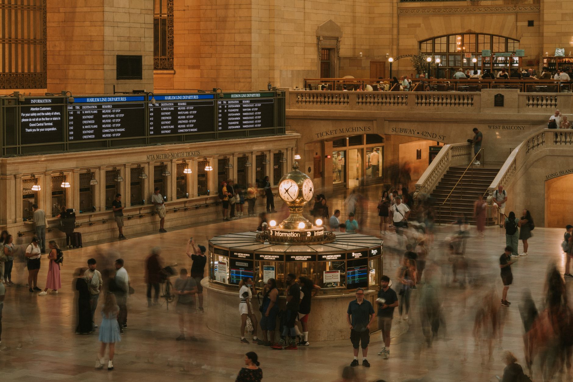 Crowd movement in Grand Central Terminal's main concourse with iconic information booth and clock.