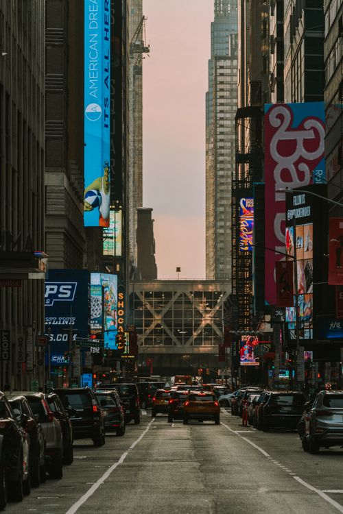 Free Vibrant street scene of New York City showcasing tall buildings and glowing billboards at dusk. Stock Photo
