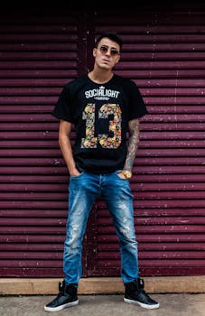 Stylish young man wearing sunglasses and a printed shirt in an urban setting.