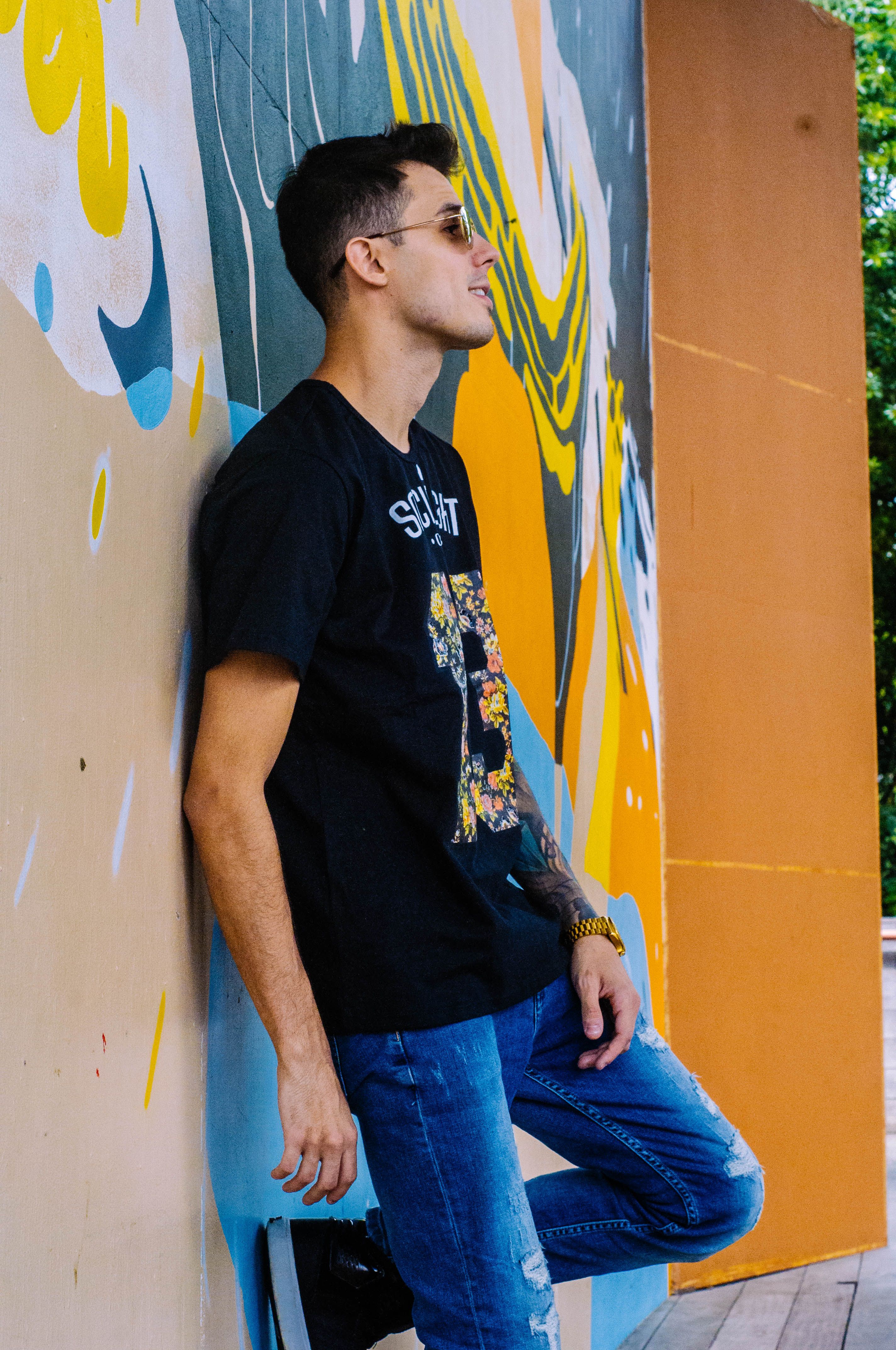 Fashionable young man posing against colorful graffiti wall, embodying urban style.