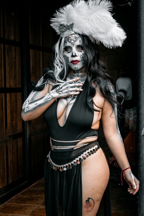 Free A gothic styled woman posing in a dramatic feathered headdress and skull makeup. Stock Photo