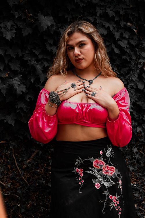 Free Stylish woman posing outdoors in pink top and floral skirt with jewelry. Stock Photo