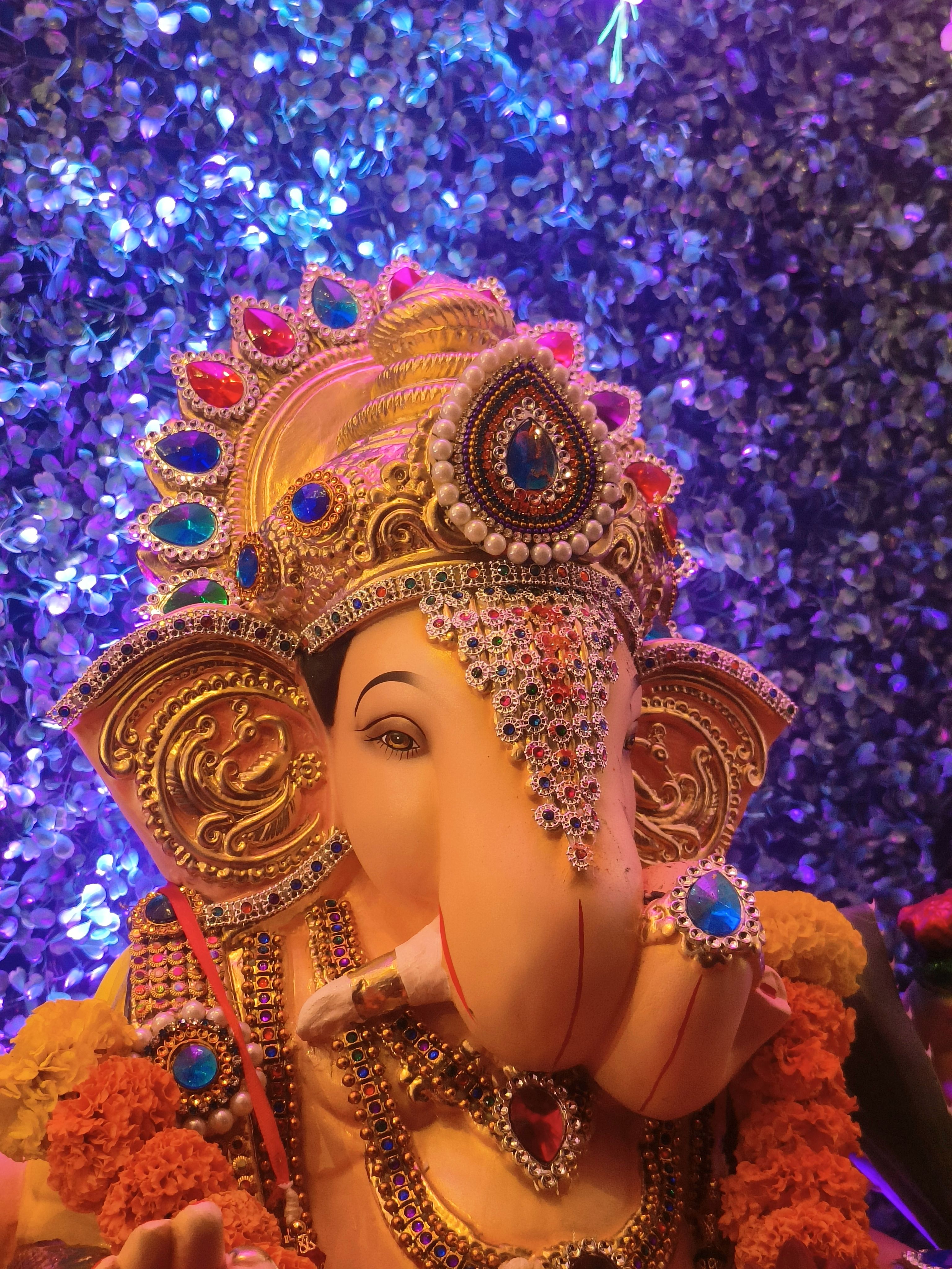 Vibrant and detailed statue of Lord Ganesha adorned with jewels and flowers.