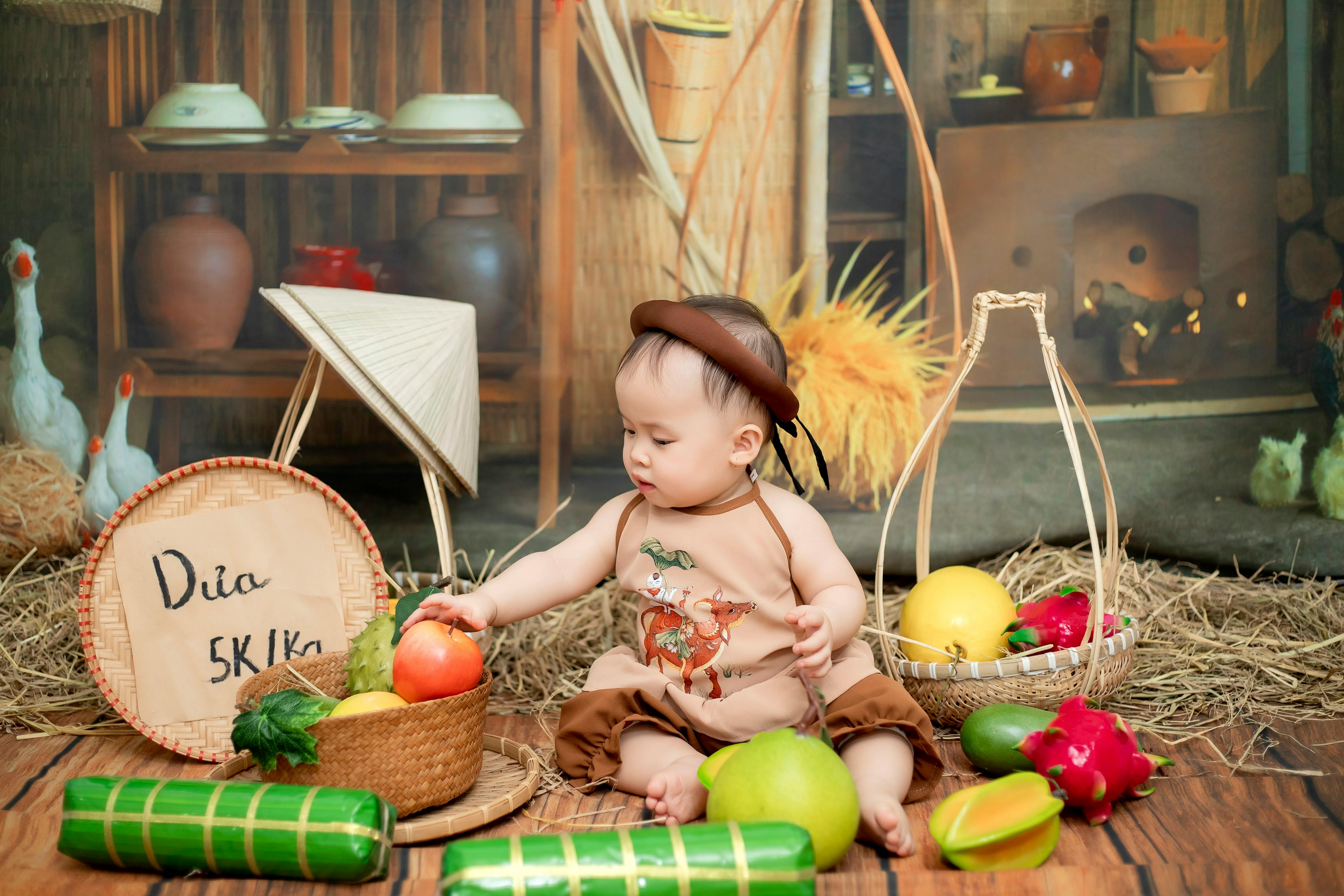 a baby sitting on a wooden floor with fruit and vegetables