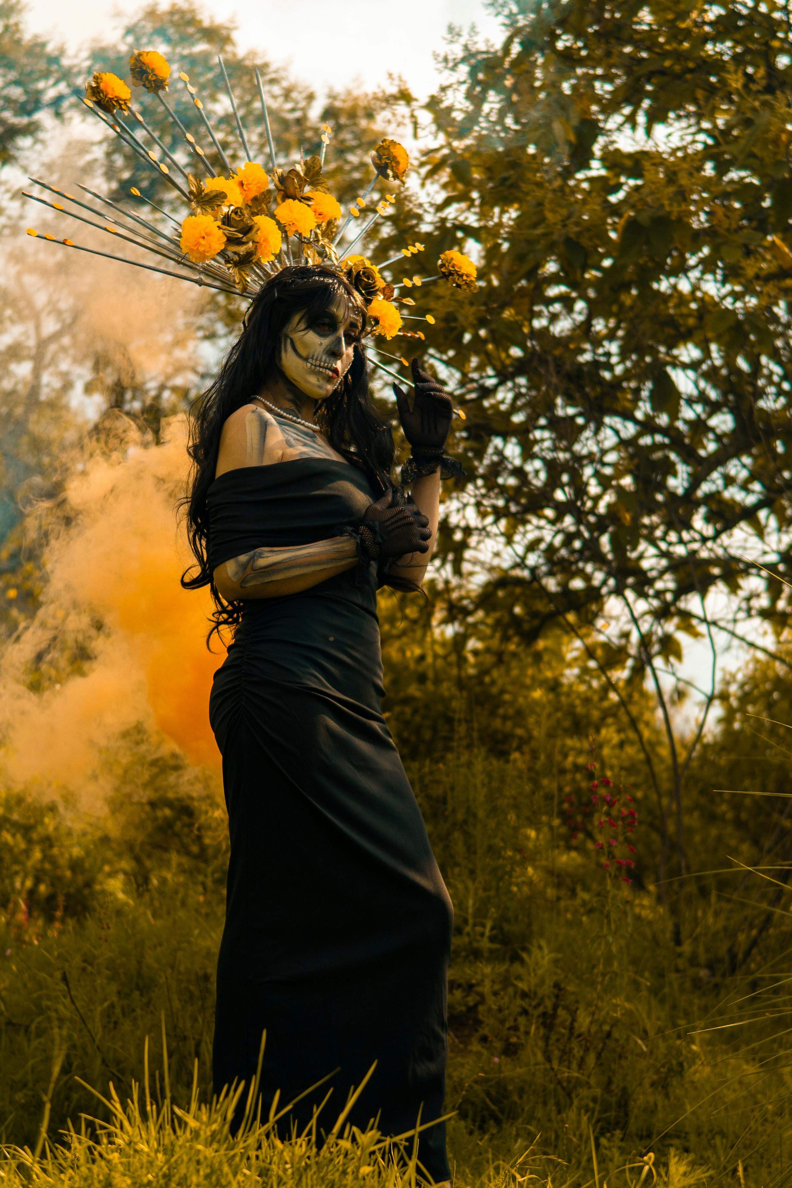 A woman dressed as a Catrina for Dia de los Muertos standing in a sunlit park in Mexico City.