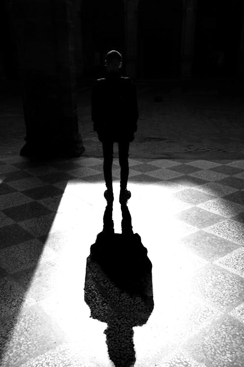 Grayscale Photography of Man Standing Under The Light