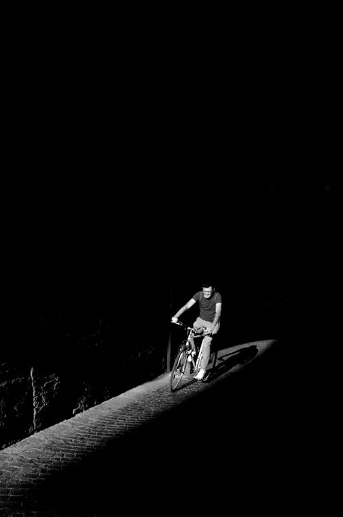 Grayscale Photo of Person Riding Bike
