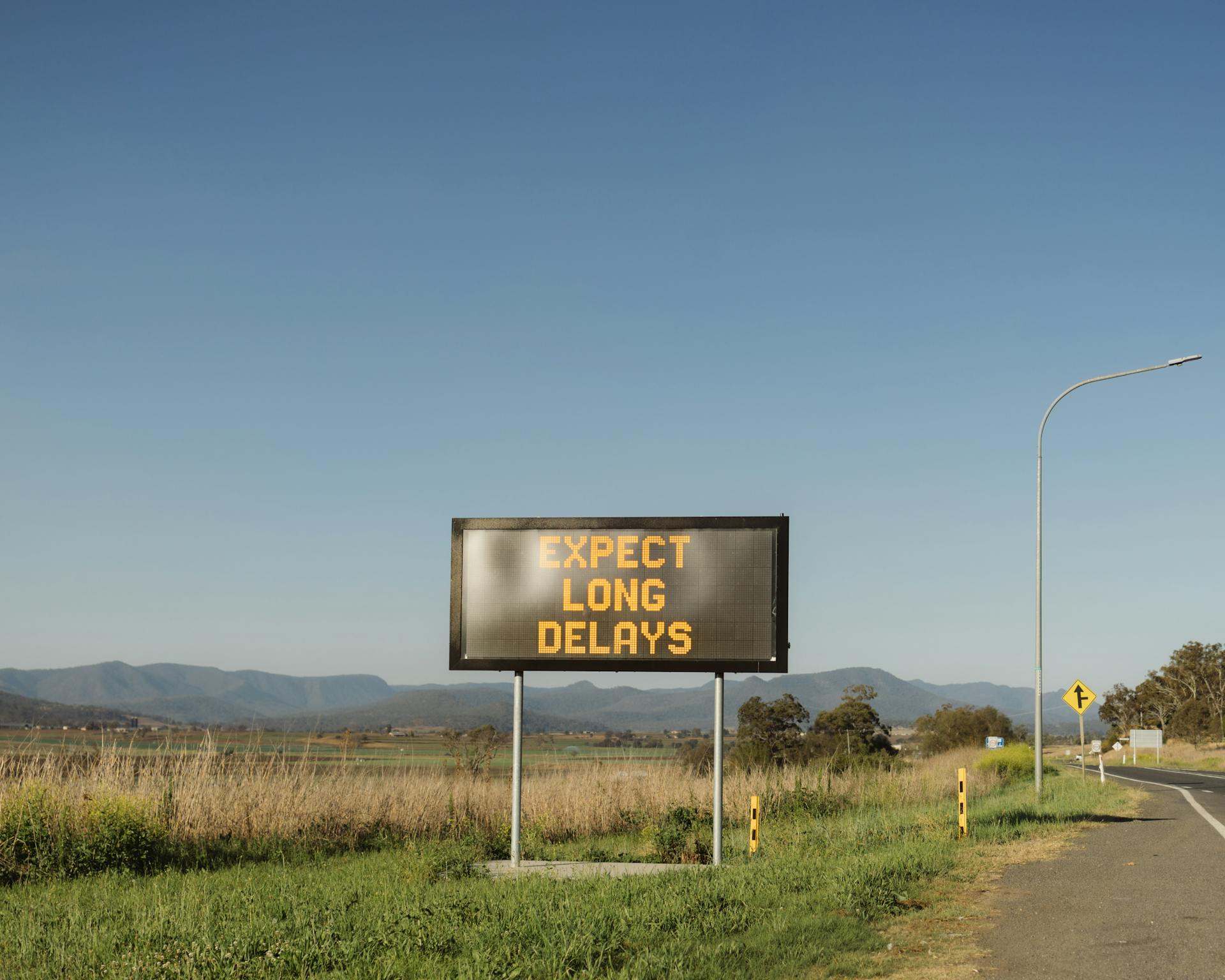 Traffic sign in Gladfield, QLD, advising of long delays ahead on a rural road.