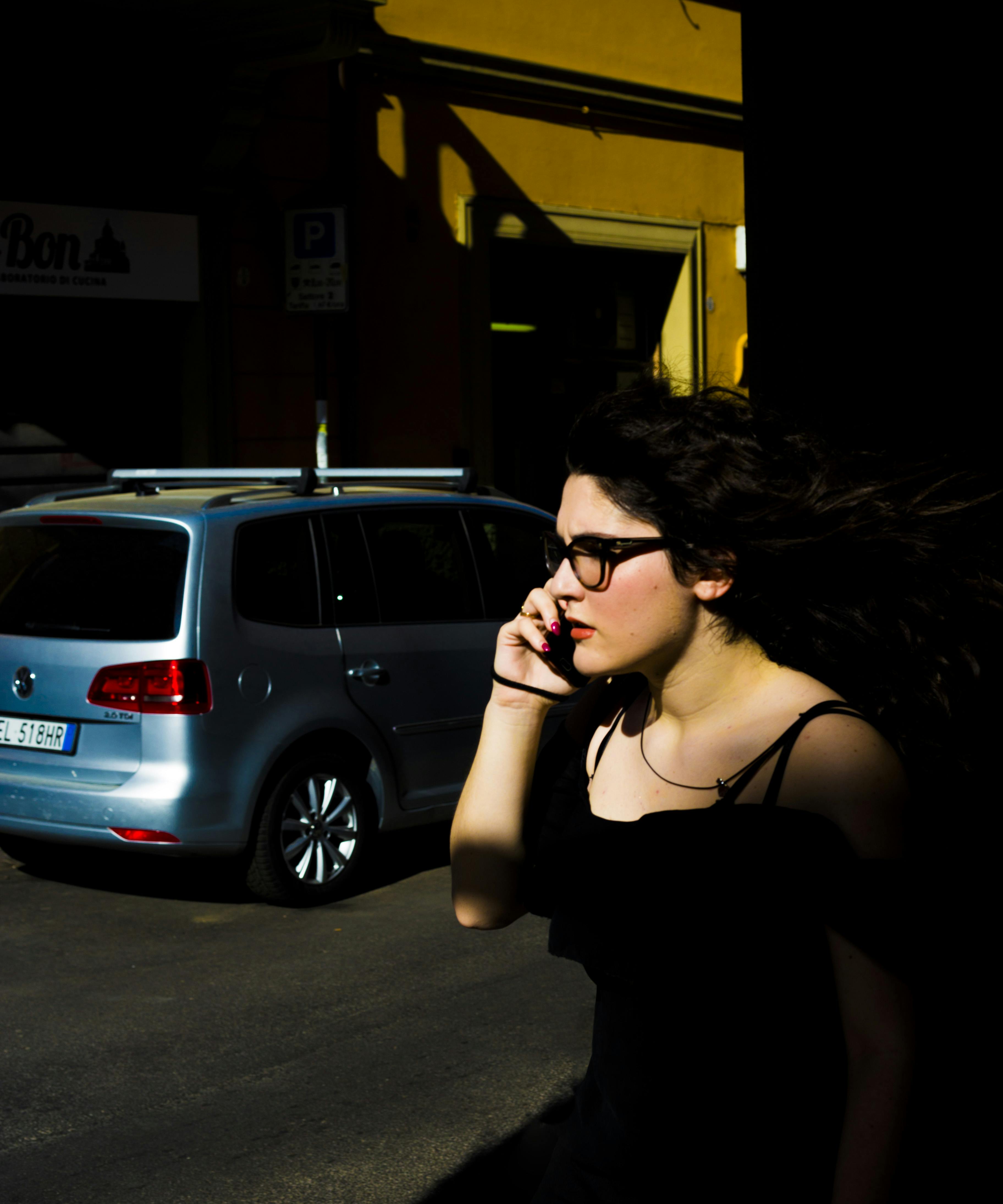 一名妇女一边打电话，一边走过城市街道，阴影被戏剧性地投射出来