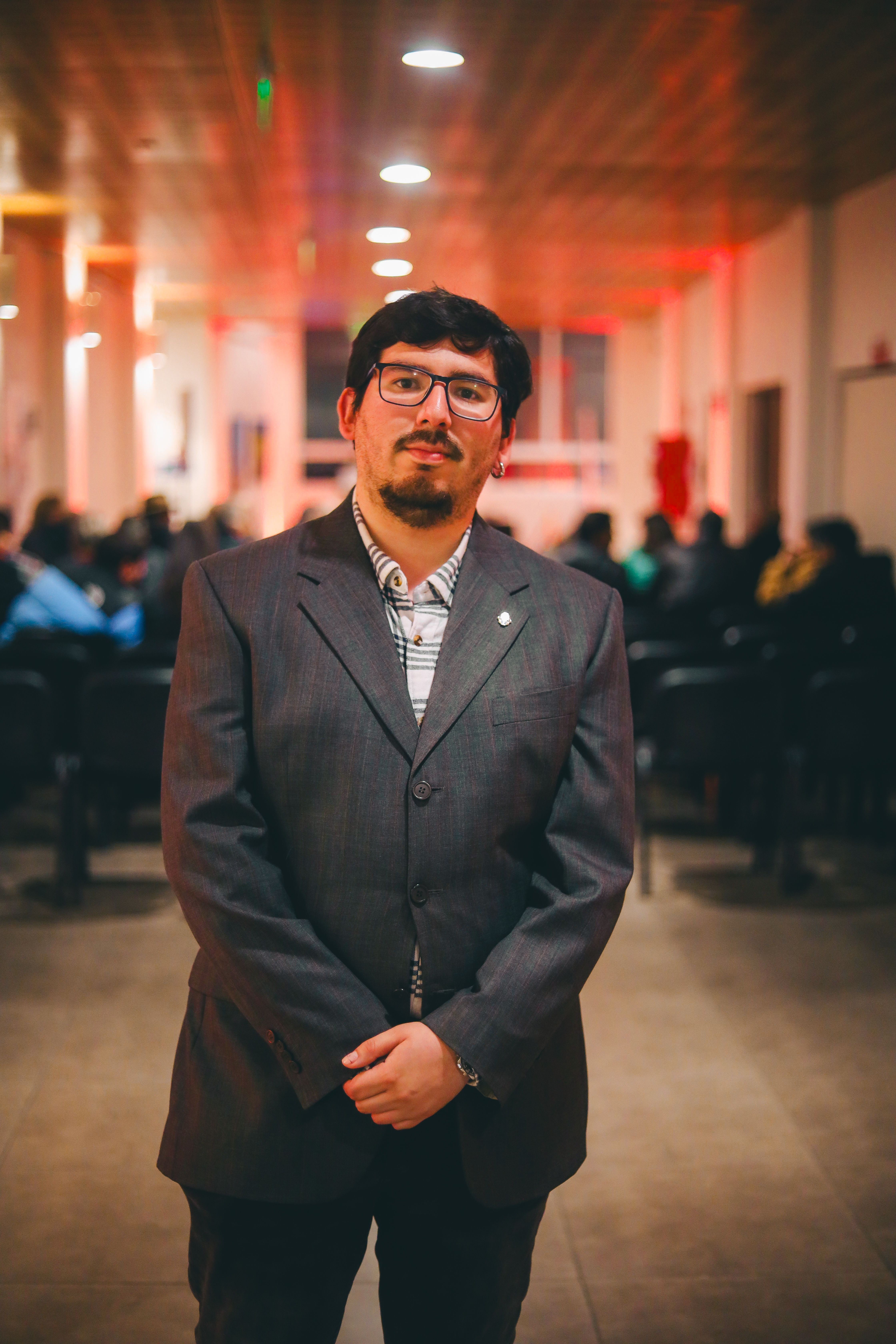 Professional portrait of a man in a suit attending an indoor business event.