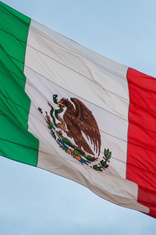 Free Close-up of the Mexican flag waving against a blue sky, symbolizing patriotism and national pride. Stock Photo