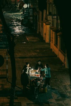 Vibrant street food vendor scene captured at night in Hanoi, showcasing local culture.