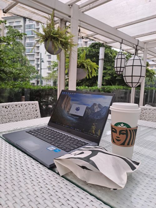 Free Cozy outdoor workspace with laptop, coffee, and snacks on a wicker table. Stock Photo