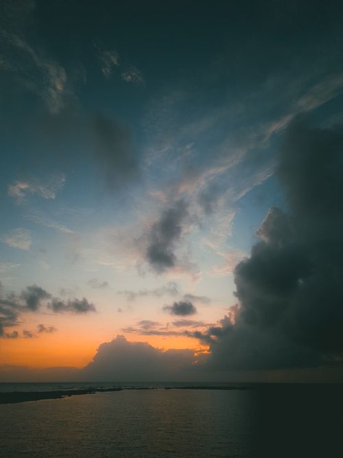 Free Captivating sunset over the ocean with dramatic storm clouds and tranquil waters. Stock Photo