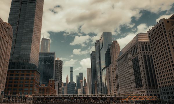 A stunning view of Chicago's skyline and river with prominent skyscrapers and bridges on a cloudy day.