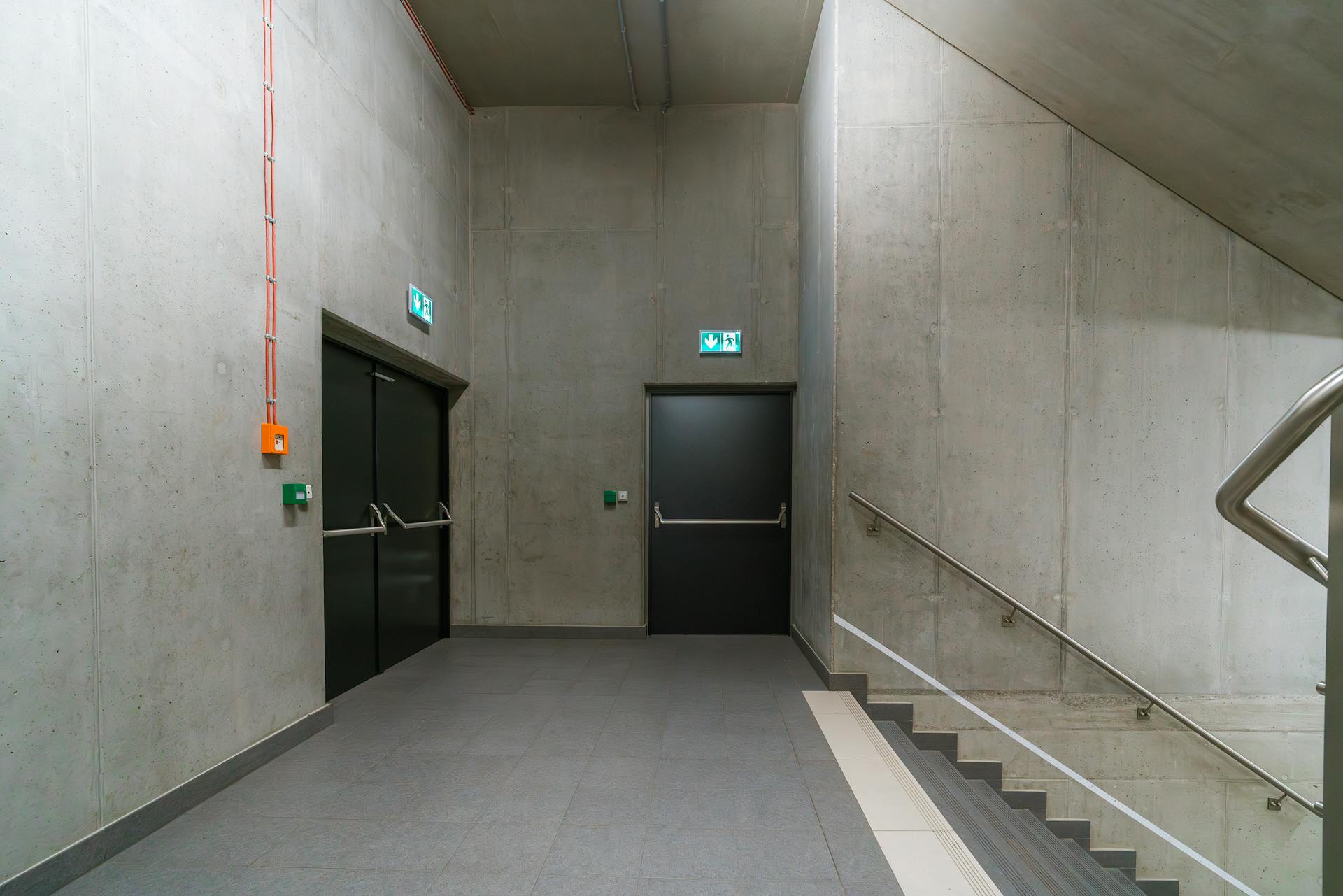 Modern indoor stairway with emergency exit doors in an industrial building.