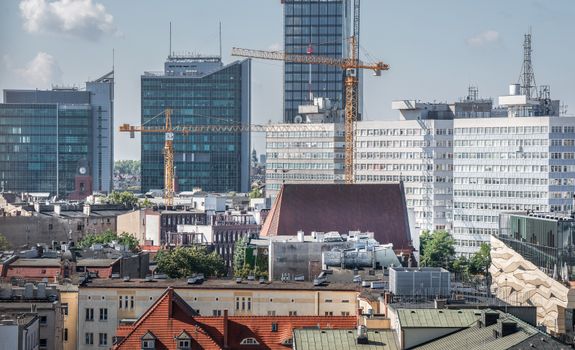 Urban skyline of Poznań with cranes and modern architecture in view.