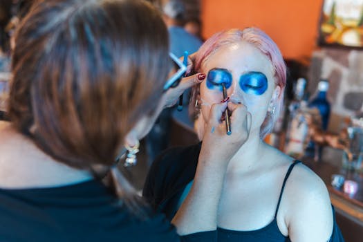 Artist applies vibrant blue makeup for Day of the Dead festival in Mexico City.