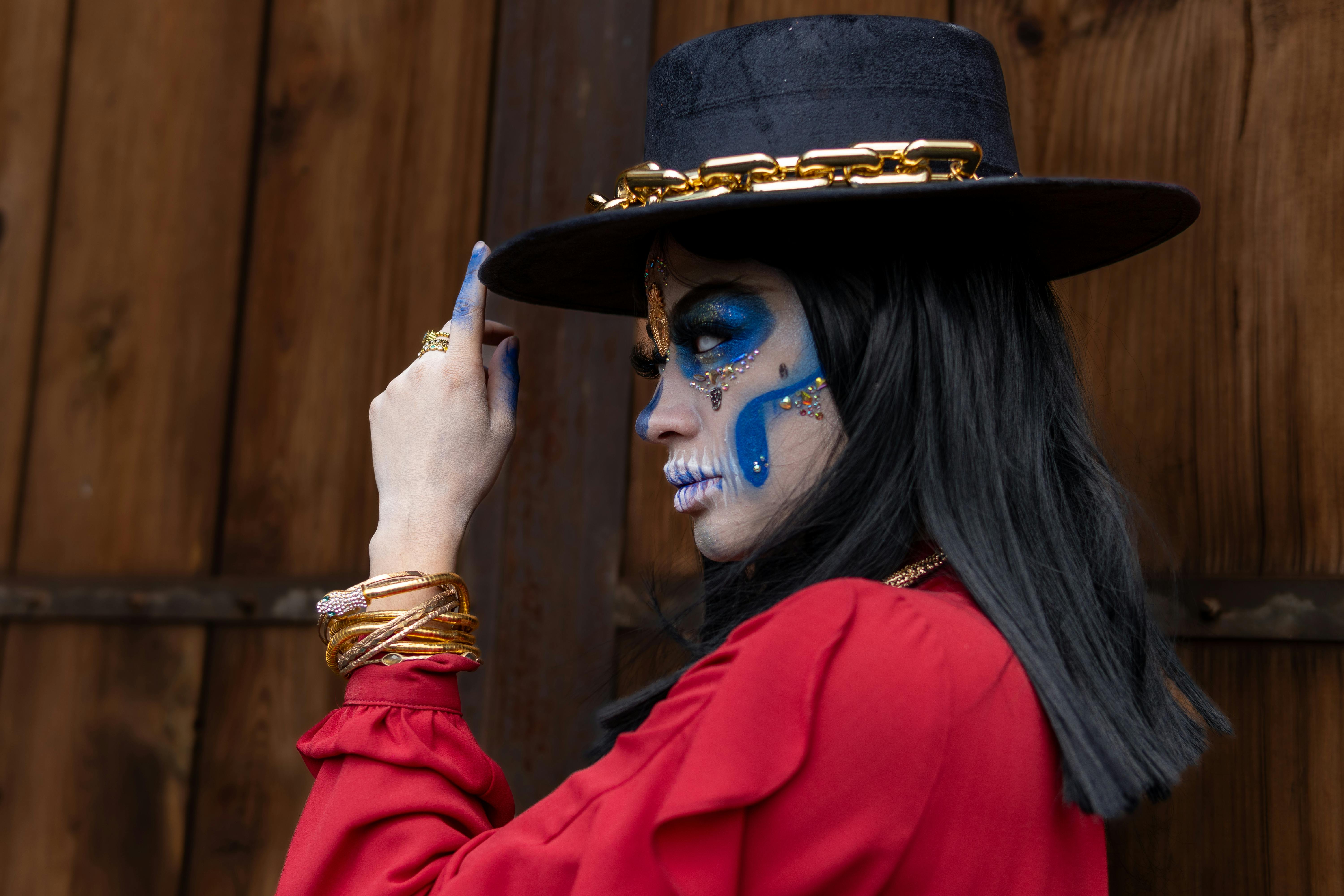 a woman in a hat and blue makeup with a blue face