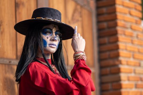 Free A woman in artistic skull makeup and traditional attire posing outdoors during the Día de los Muertos festival. Stock Photo