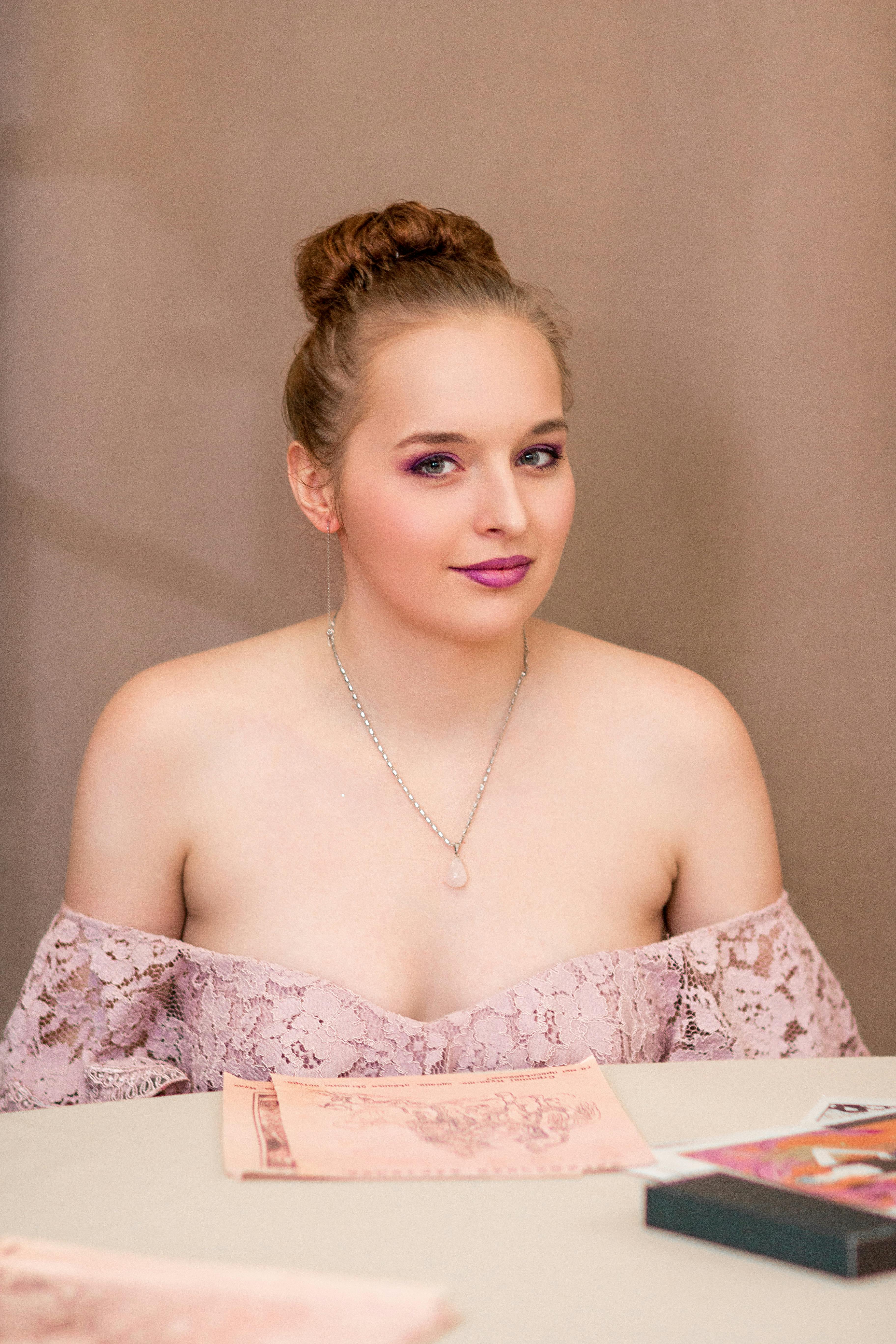 a young woman in a pink dress sitting at a table