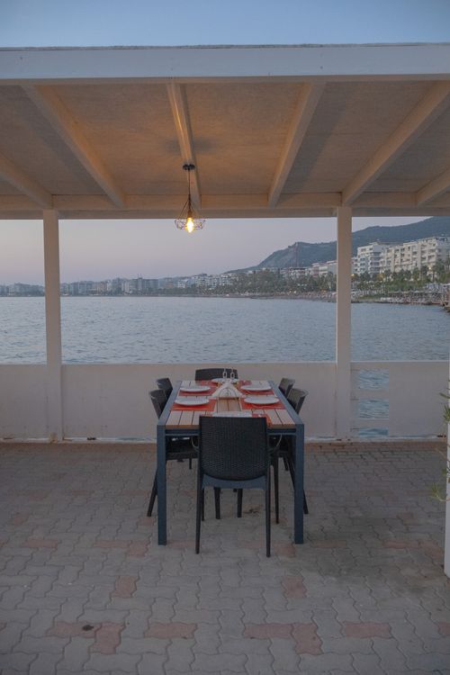 Free Outdoor dining setup overlooking the sea in Vlora, Albania at sunset. Stock Photo