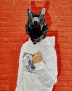 Cyberpunk Masked Individual Against Red Brick Wall