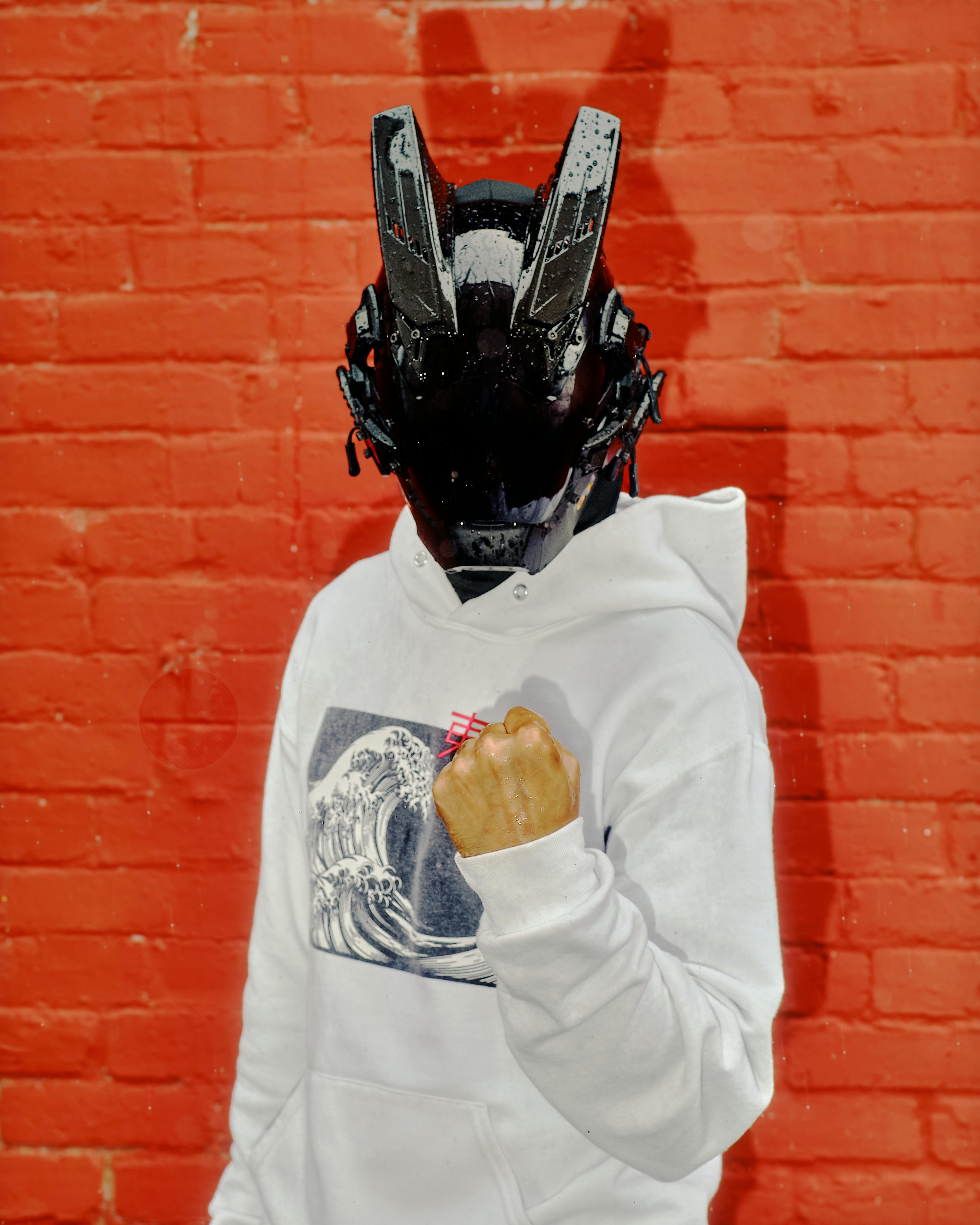 De franc Individu Emmascarat De Cyberpunk Contra Un Mur De Maó Vermell Foto d'estoc