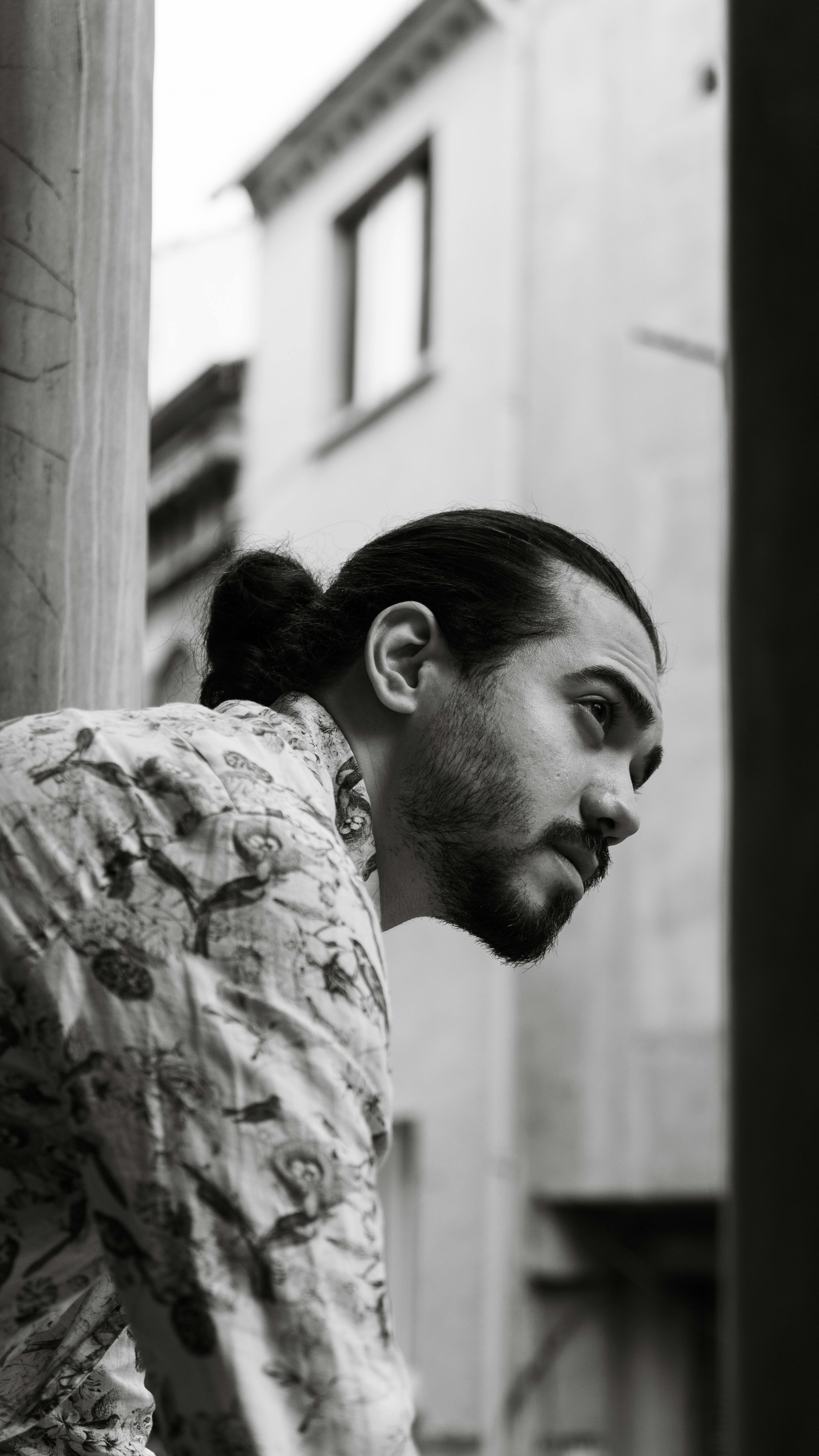 Black and white portrait of a man in urban setting, exuding a contemplative mood.