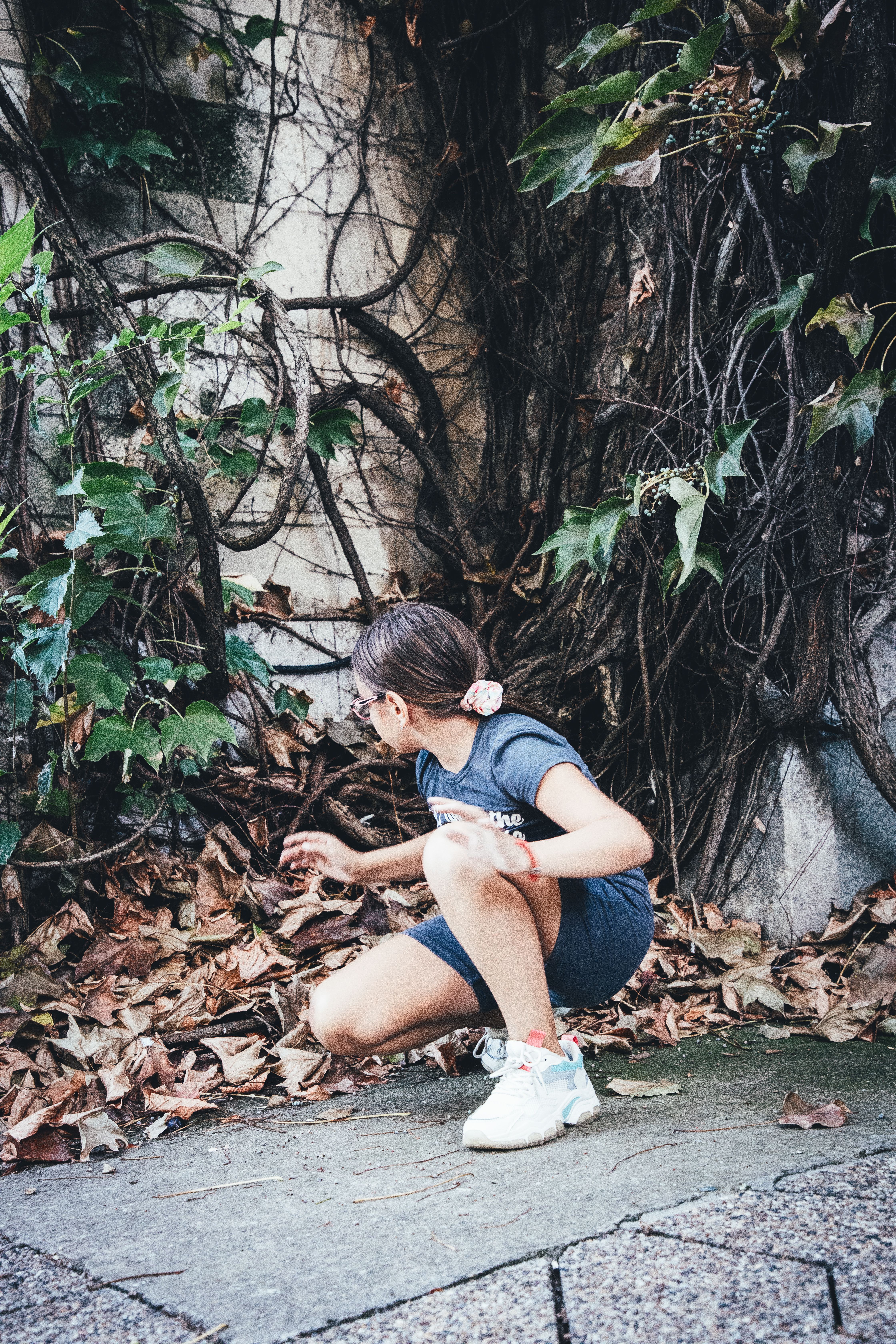 Girl Crouching near Roots and Plants in Corner at Park · Free Stock Photo