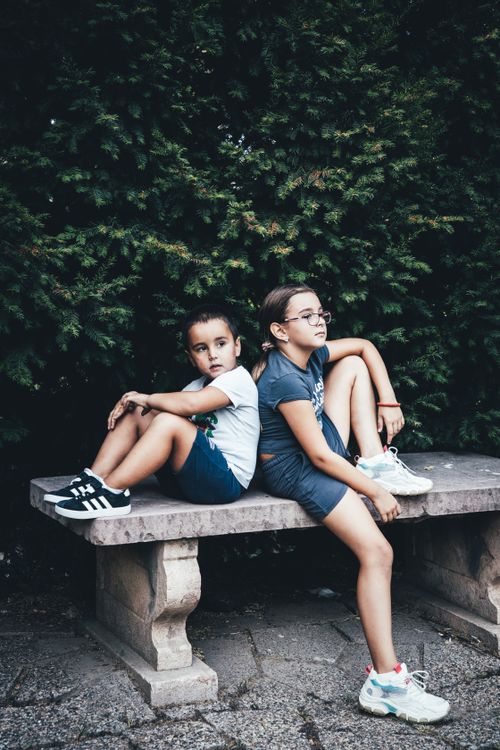 Free Two children sit on a stone bench outdoors, enjoying each other's company. Stock Photo