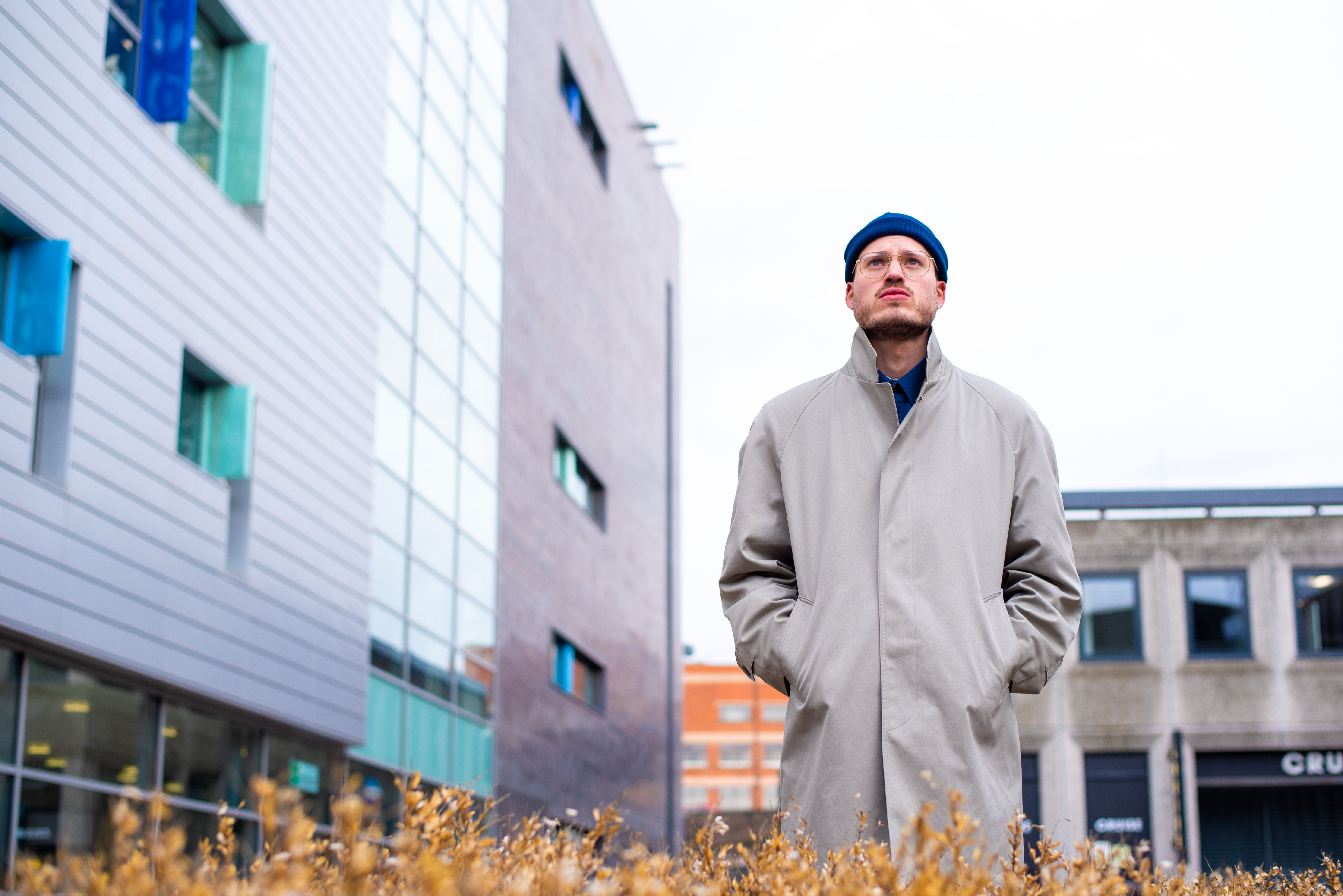 A man in a coat standing in front of a building · Free Stock Photo