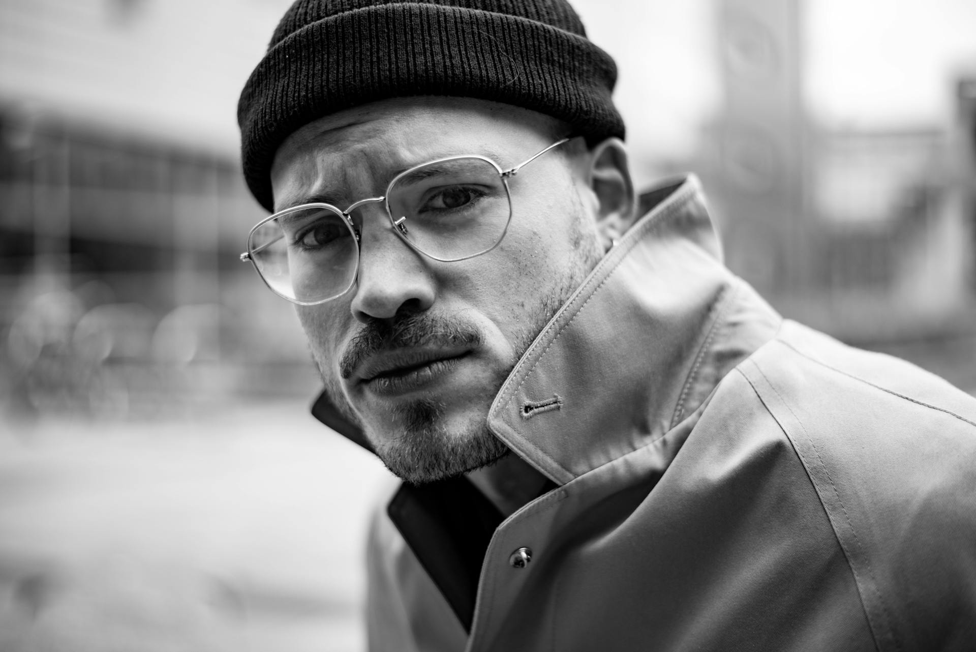 Black and White Photo of a Man in Eyeglasses Wearing a Coat and a Hat