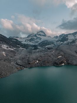 A breathtaking aerial shot of a mountain landscape with glacier and lake.